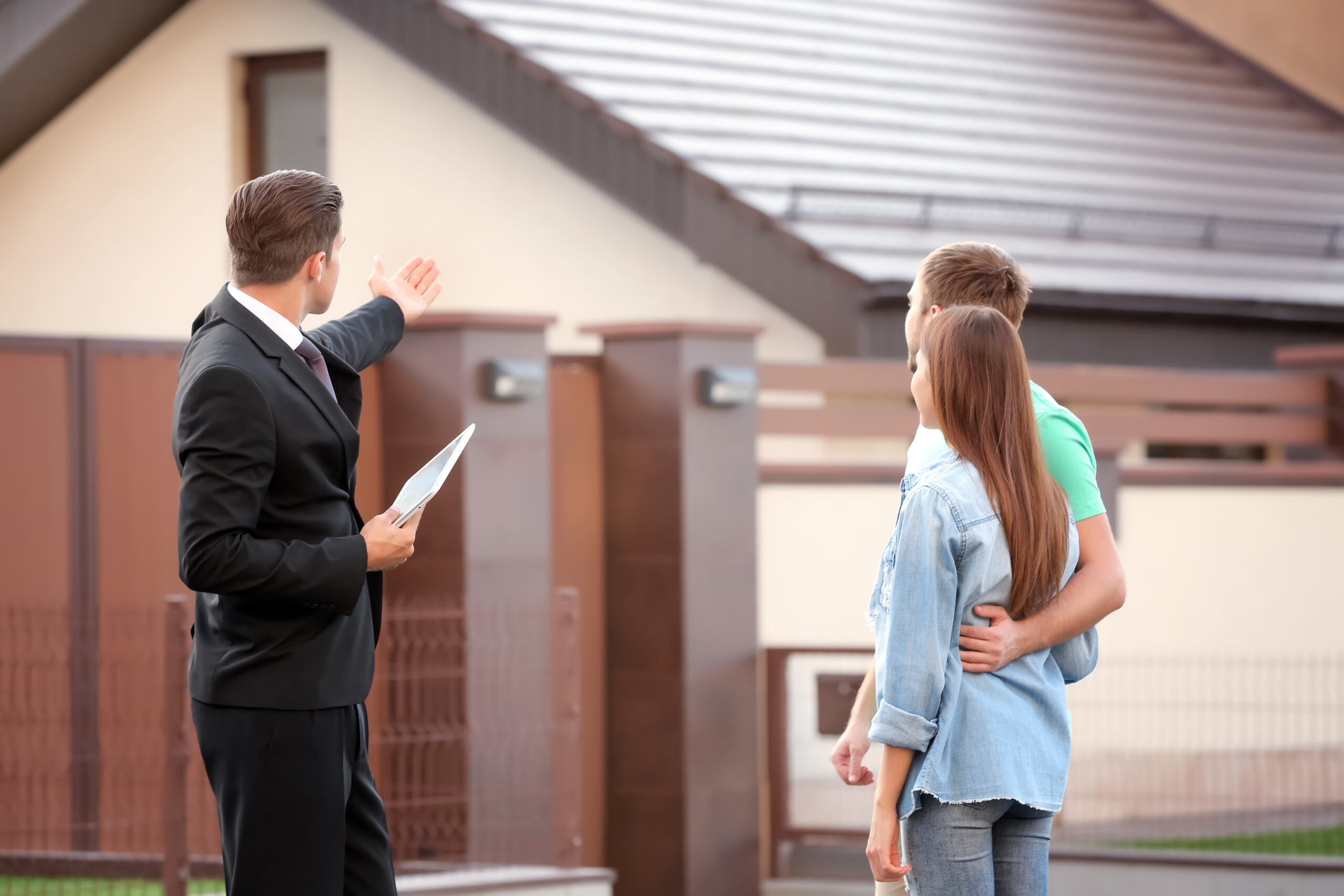 Young couple with real estate agent near house