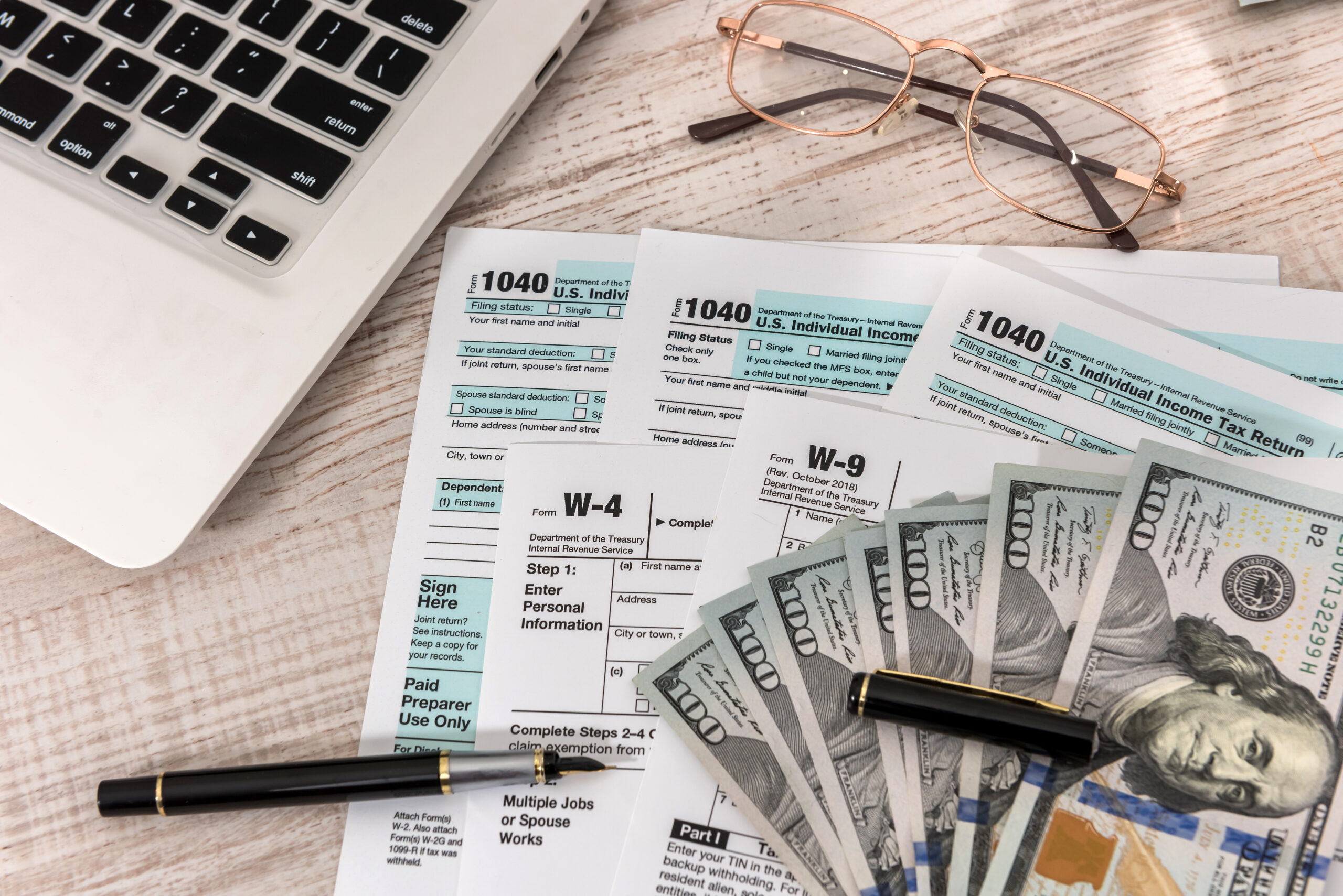 us 1040 tax form with pen, dollar and laptop at office. tax time